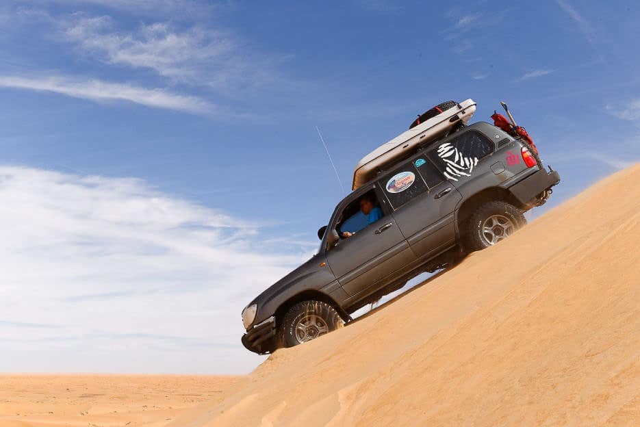 4x4 qui descend la pente d'une dune dans le désert